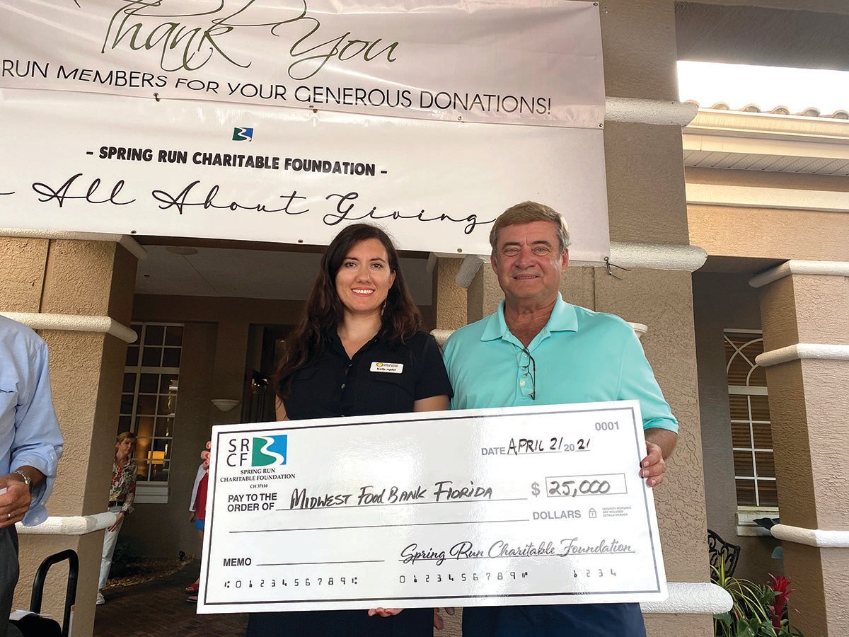 Kelly Apfel, marketing and development manger at Midwest Food Bank of Florida recieves $25,000 check from Spring Run Foundation member Randy Blanton.